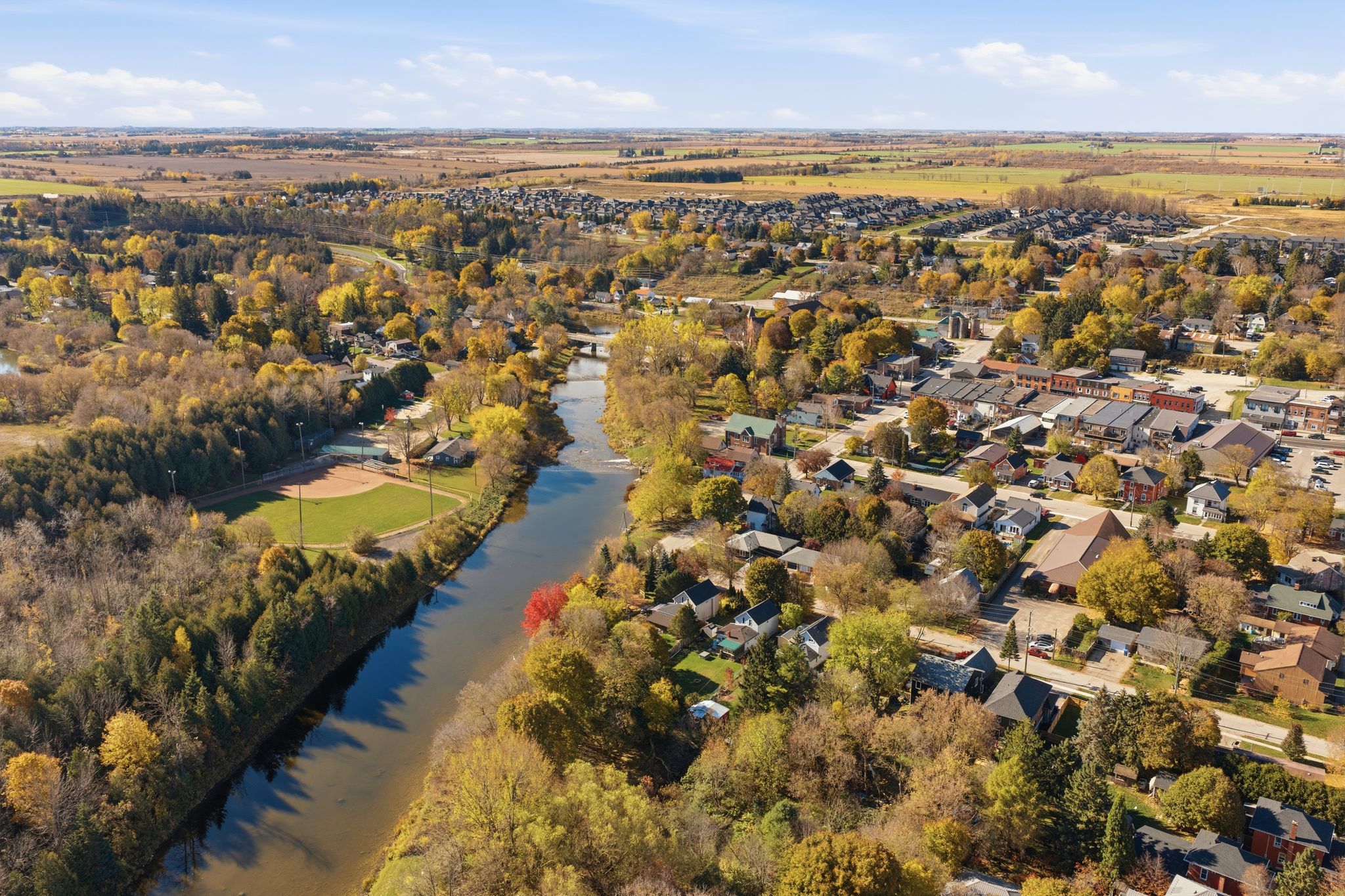 Aerial view of Grand Valley and the Grand River in autumn, with farmland beyond the town