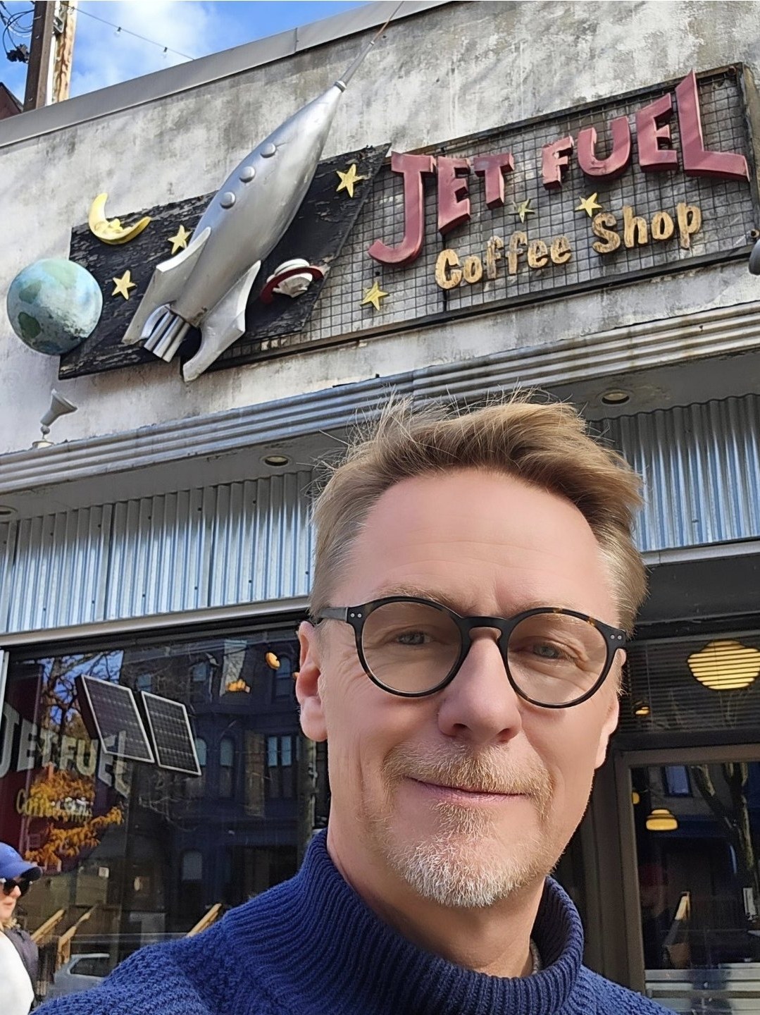 Jim Emilson in front of Jet Fuel Coffee Shop in Cabbagetown, under the rocket sign