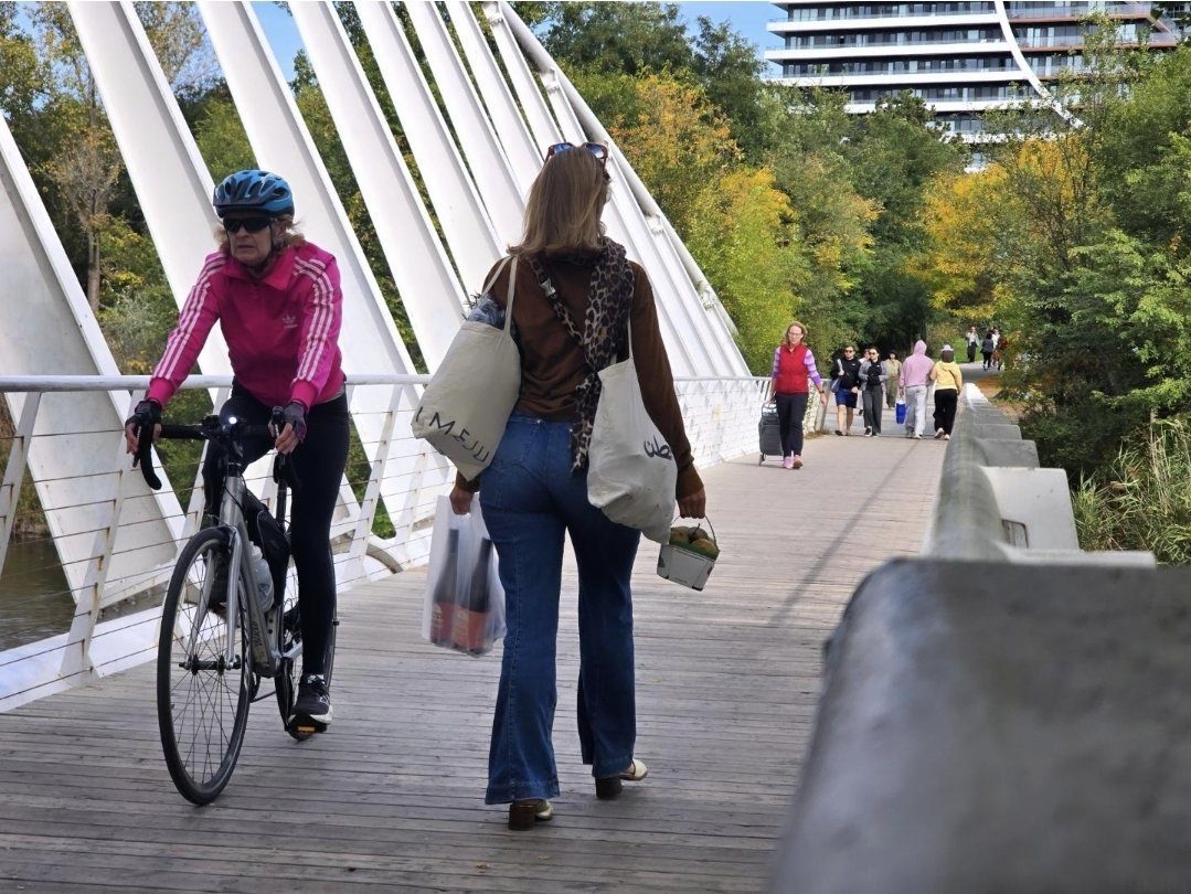 Market shopper with full bags crossing the Mimico Creek footbridge
