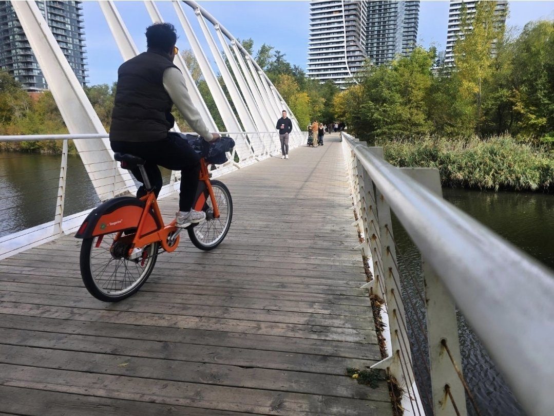 Cyclist crossing the footbridge over Mimico Creek toward the Humber Bay Shores Farmers' Market