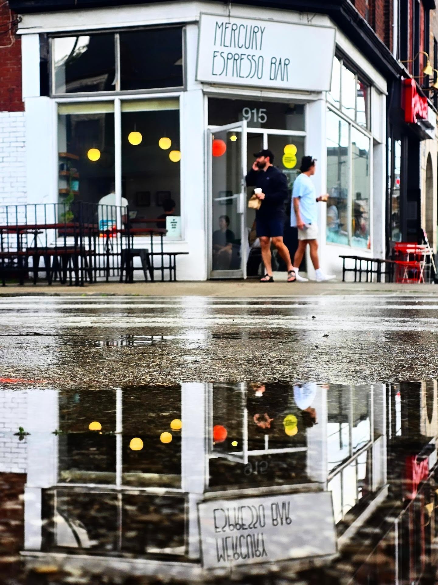 Mercury Espresso Bar storefront on Queen Street East, glowing across a wet street