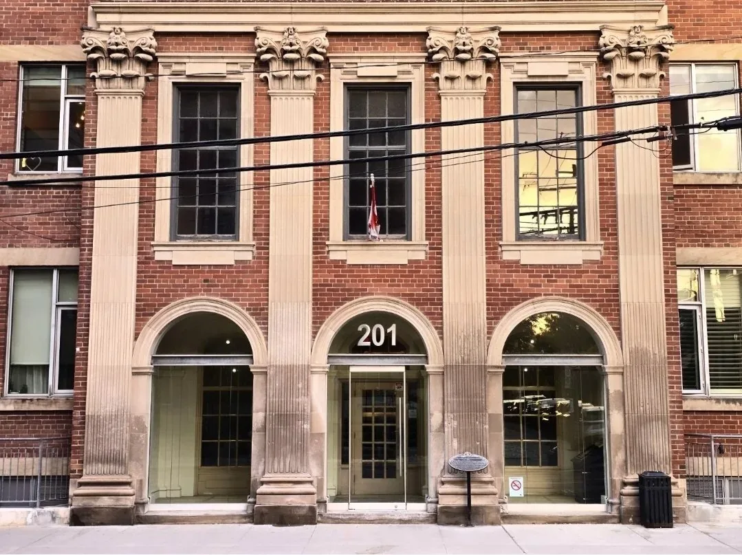 Printing Factory Lofts at 201 Carlaw Ave, Toronto: heritage stone portico entrance with three arches, Rolph Clark Stone ghost sign on the brick above