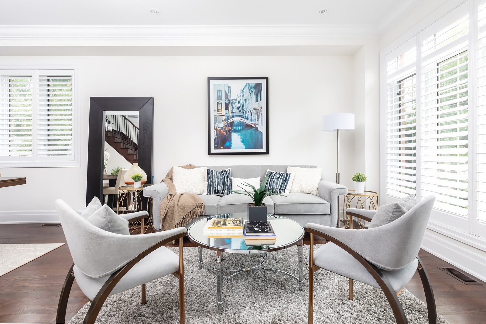 Staged living room with a grey sofa and plantation shutters at 106A Hollis Avenue in the Beach, Toronto