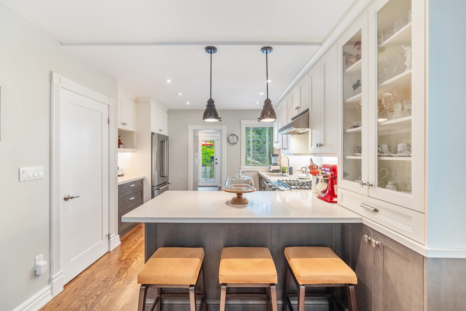 Staged kitchen with a large island and mustard bar stools at 193 Lawlor Avenue, Toronto