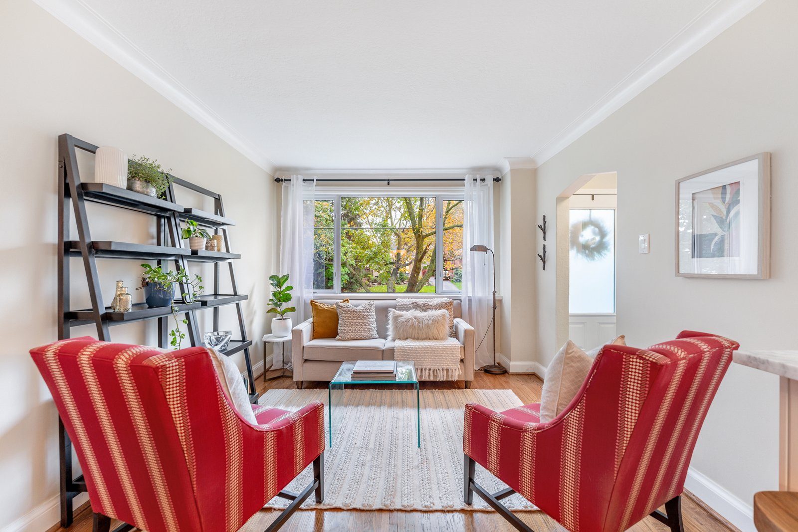 Staged living room with red striped chairs and a ladder shelf at 64 Delroy Drive, Toronto