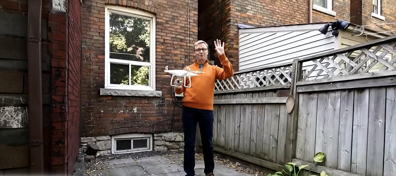 Jim Emilson waving at the camera, drone in hand, at the 2016 listing for 589 Runnymede Avenue in Toronto's Junction neighbourhood