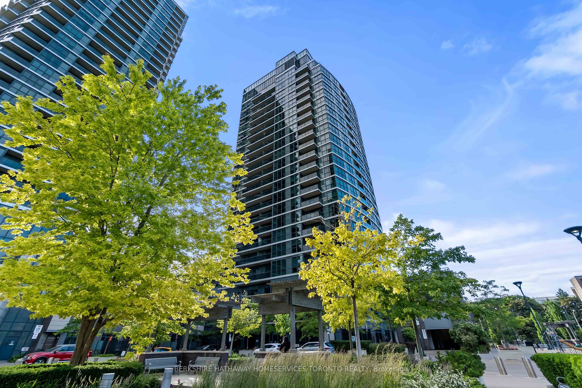 Street-level view of the glass One Valhalla tower at 1 Valhalla Inn Road, Toronto, framed by trees