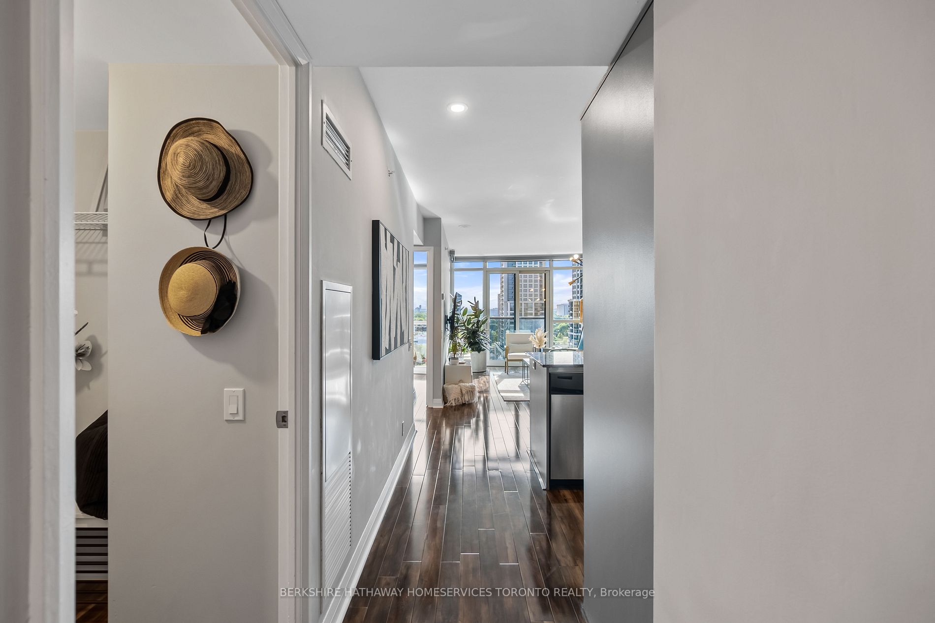 Hallway view through Suite 1305 toward the living room and kitchen island, with floor-to-ceiling west-facing windows beyond