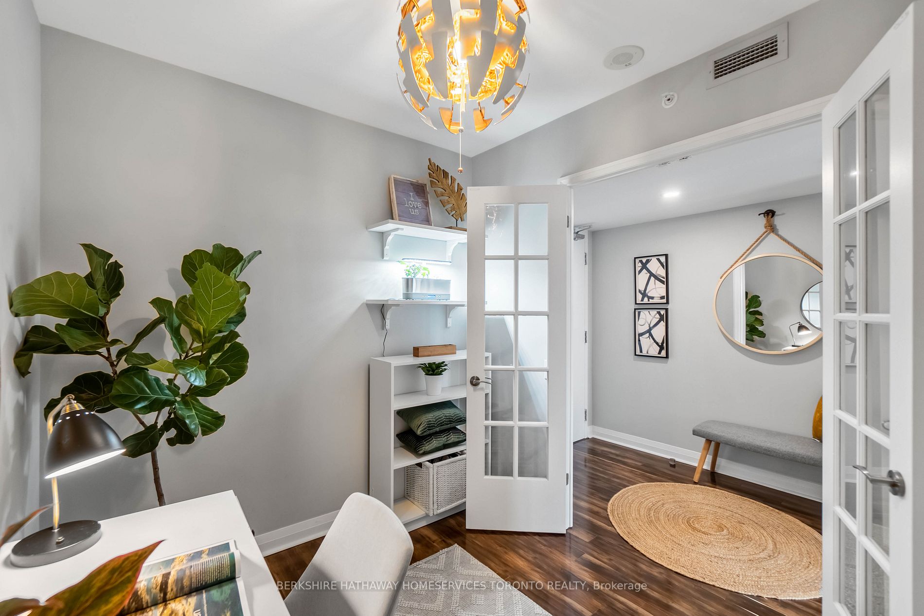 Den detail with sculptural pendant light and french doors opening to the foyer