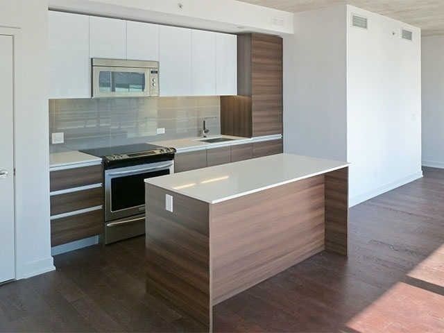 Open kitchen at Unit 914 with white upper cabinets, wood-grain lower cabinets, and a large island