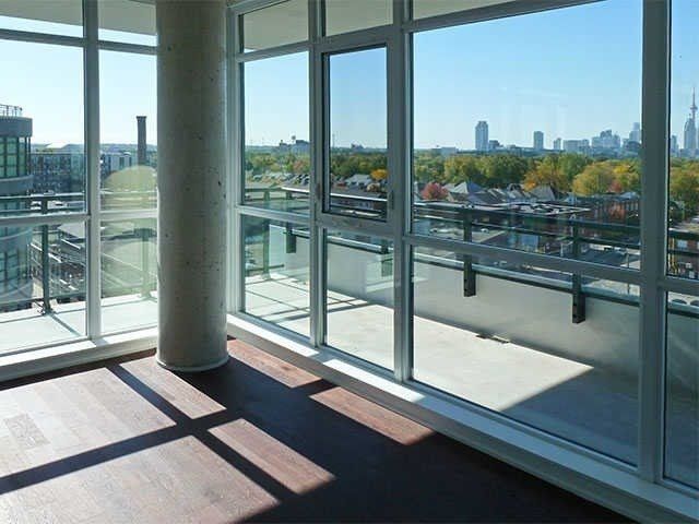 The corner window wall at Unit 914 with a round concrete column, balcony doors, and the skyline beyond