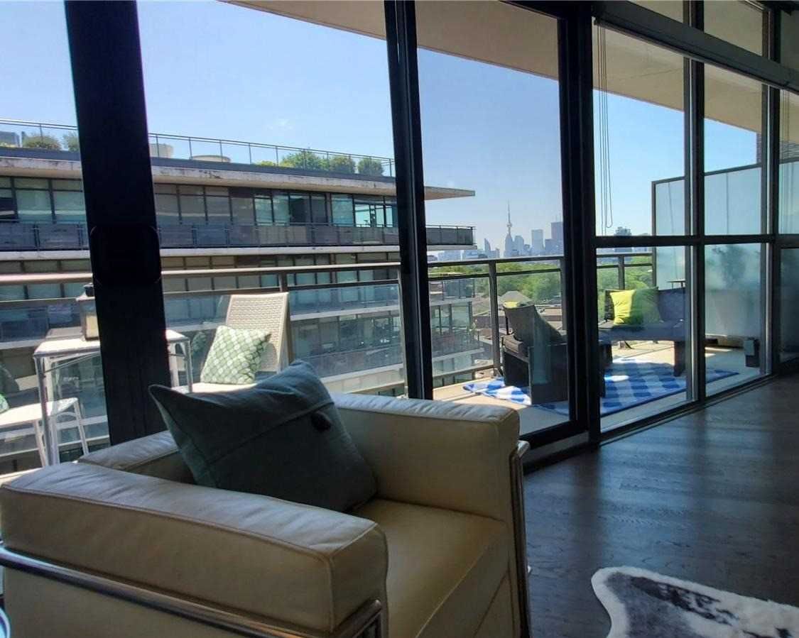 Living room at Unit 901 with cream armchair, floor-to-ceiling windows, and the balcony beyond