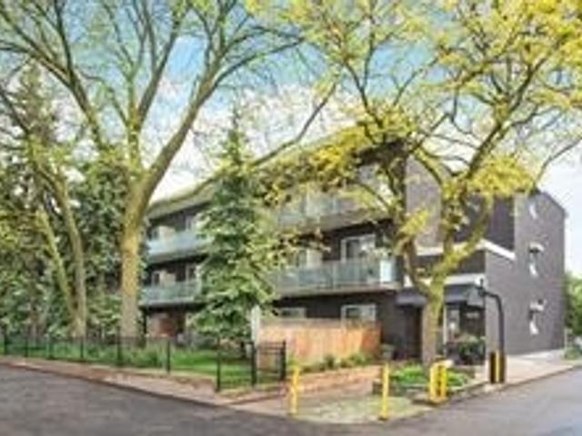 Exterior of the low-rise condominium building at 123 Woodbine Avenue, Toronto, framed by mature trees
