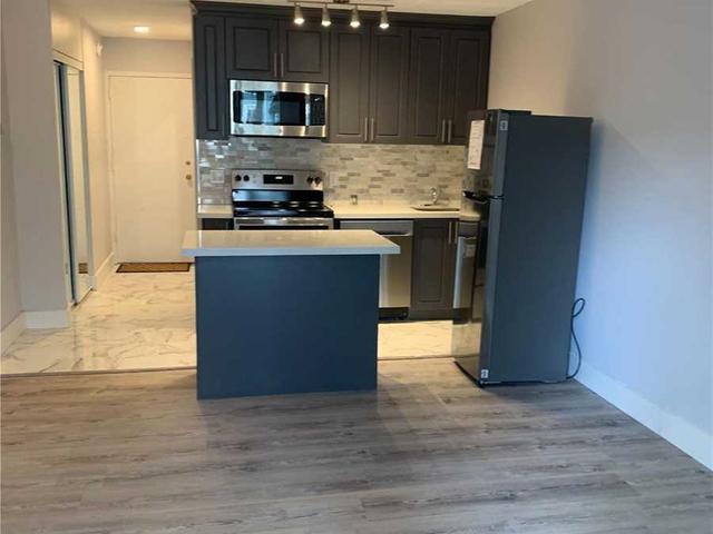 Renovated kitchen with dark cabinets, stainless steel appliances, island with breakfast bar and track lighting