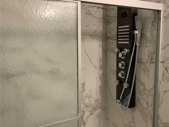 Renovated bathroom with marble-look tile and upgraded rain shower panel