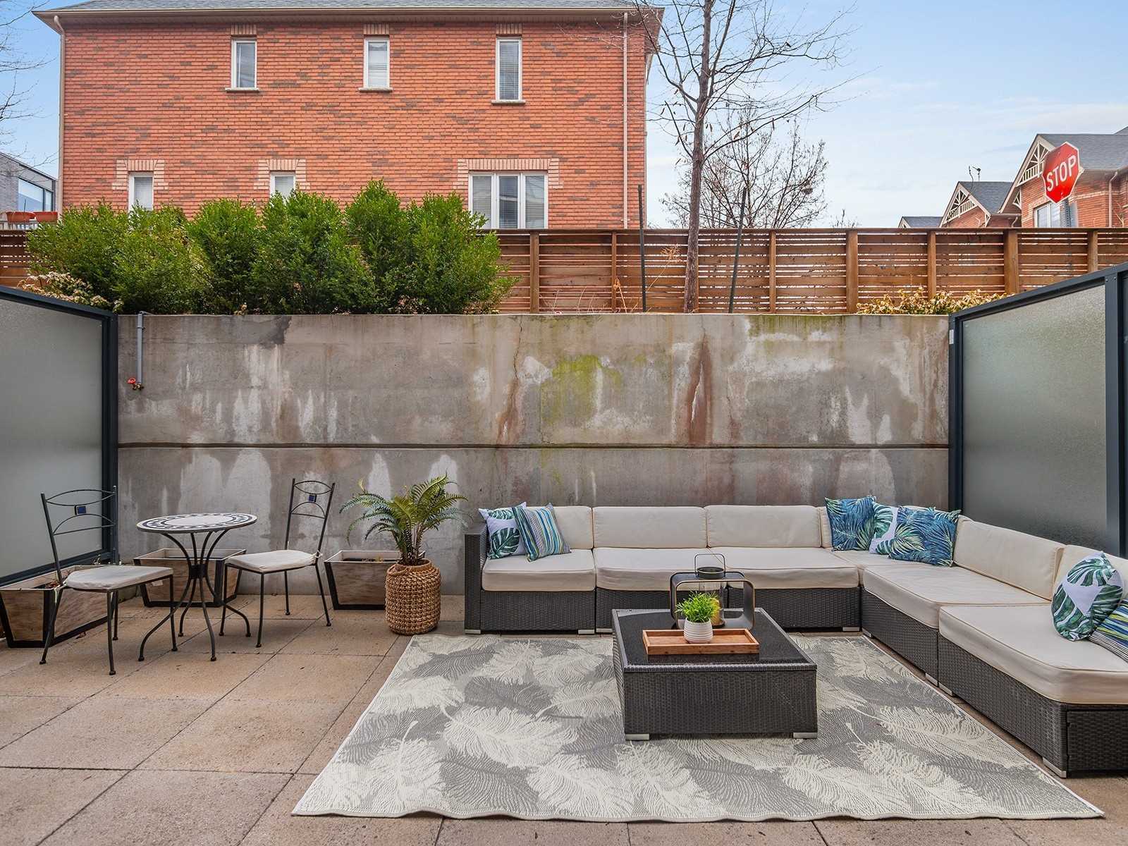 Private 300 sq ft patio at Unit TH104 with outdoor sectional sofa, dining set, and privacy screens