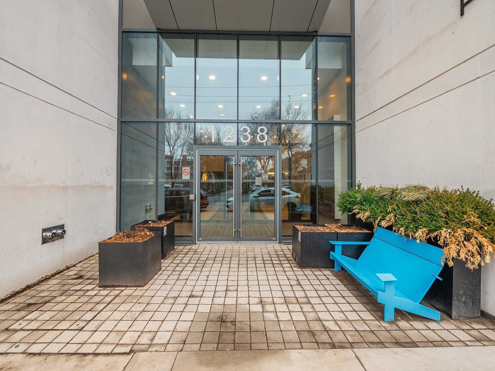 Entrance of 1238 Dundas Street East with 1238 on the glass doors and a blue bench