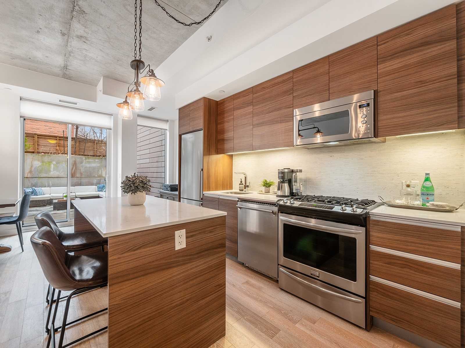 Gourmet kitchen with stainless steel gas range, microwave, dishwasher, and walnut cabinetry
