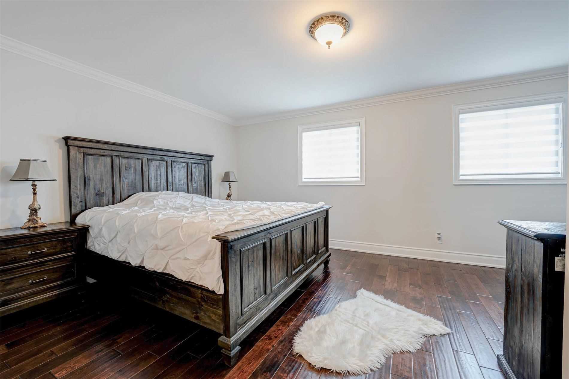 Primary bedroom with wooden bed frame and two windows
