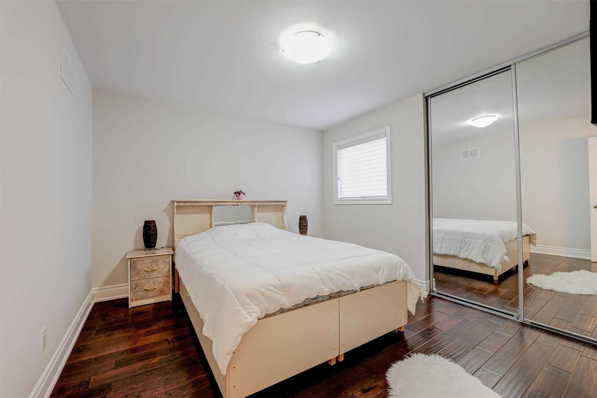 Bedroom with mirrored closet doors and hardwood floors