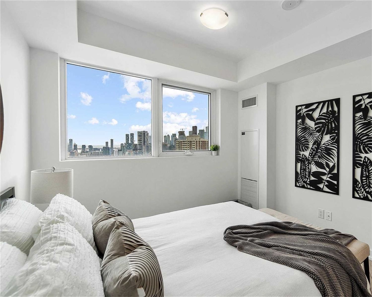 Staged bedroom at Suite 2308 with large windows and downtown skyline views