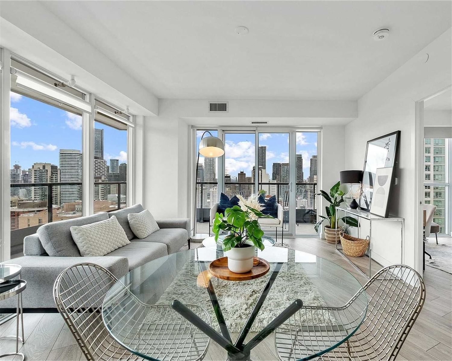 Bright staged living and dining room at Suite 2308 with floor-to-ceiling windows and downtown skyline views