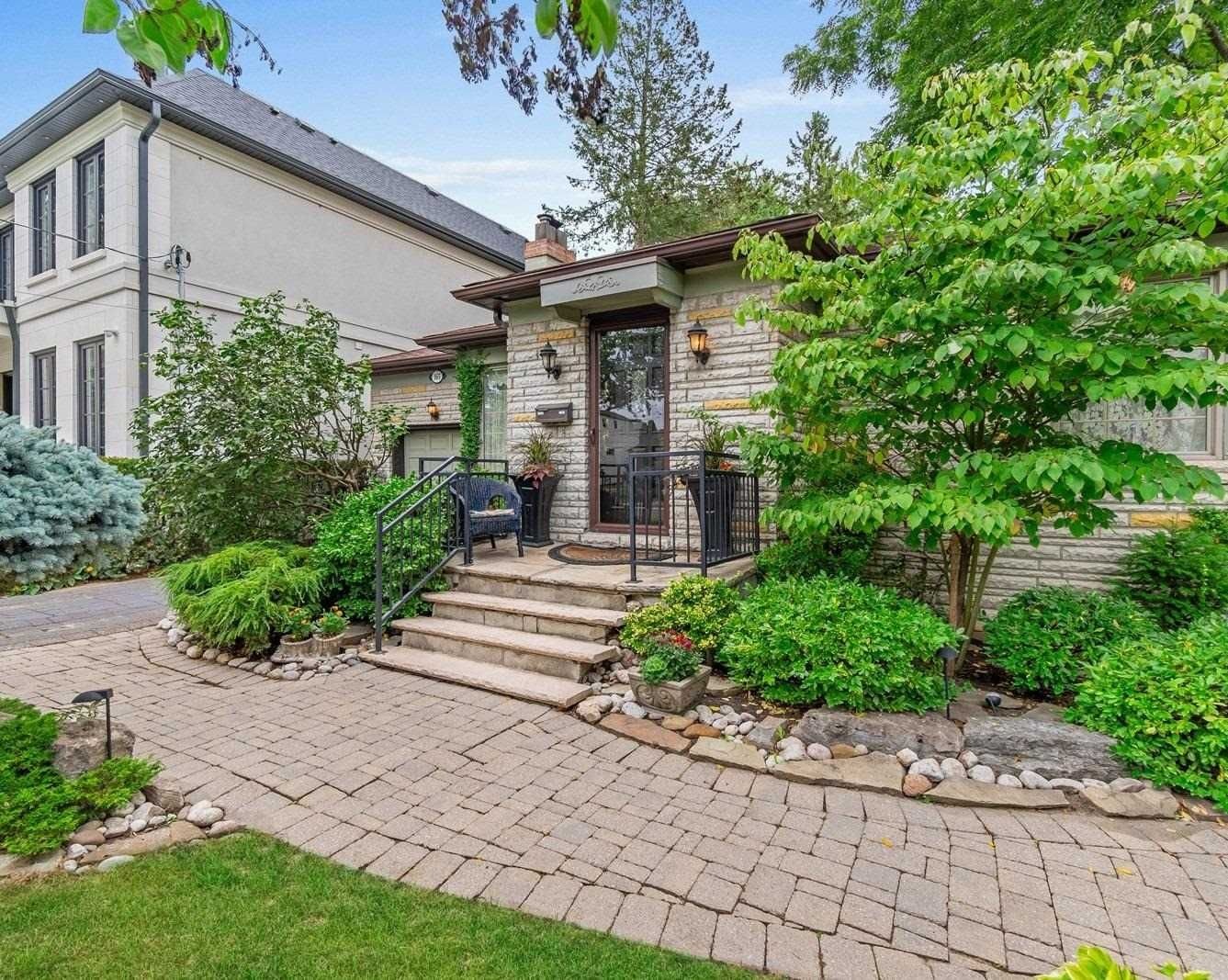 Front exterior of the detached brick bungalow at 165 The Kingsway, Toronto, with landscaped gardens and stone walkway