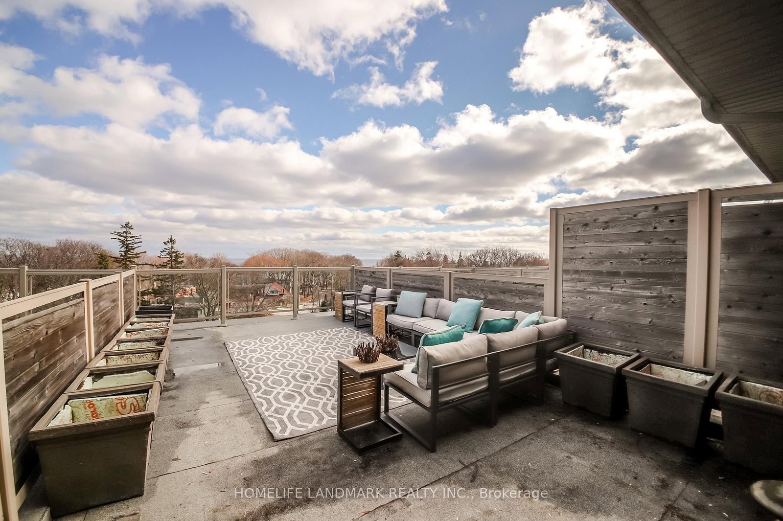 The rooftop terrace at 1733 Kingston Road, Toronto — lounge seating, patterned rug and lake views over Birch Cliff