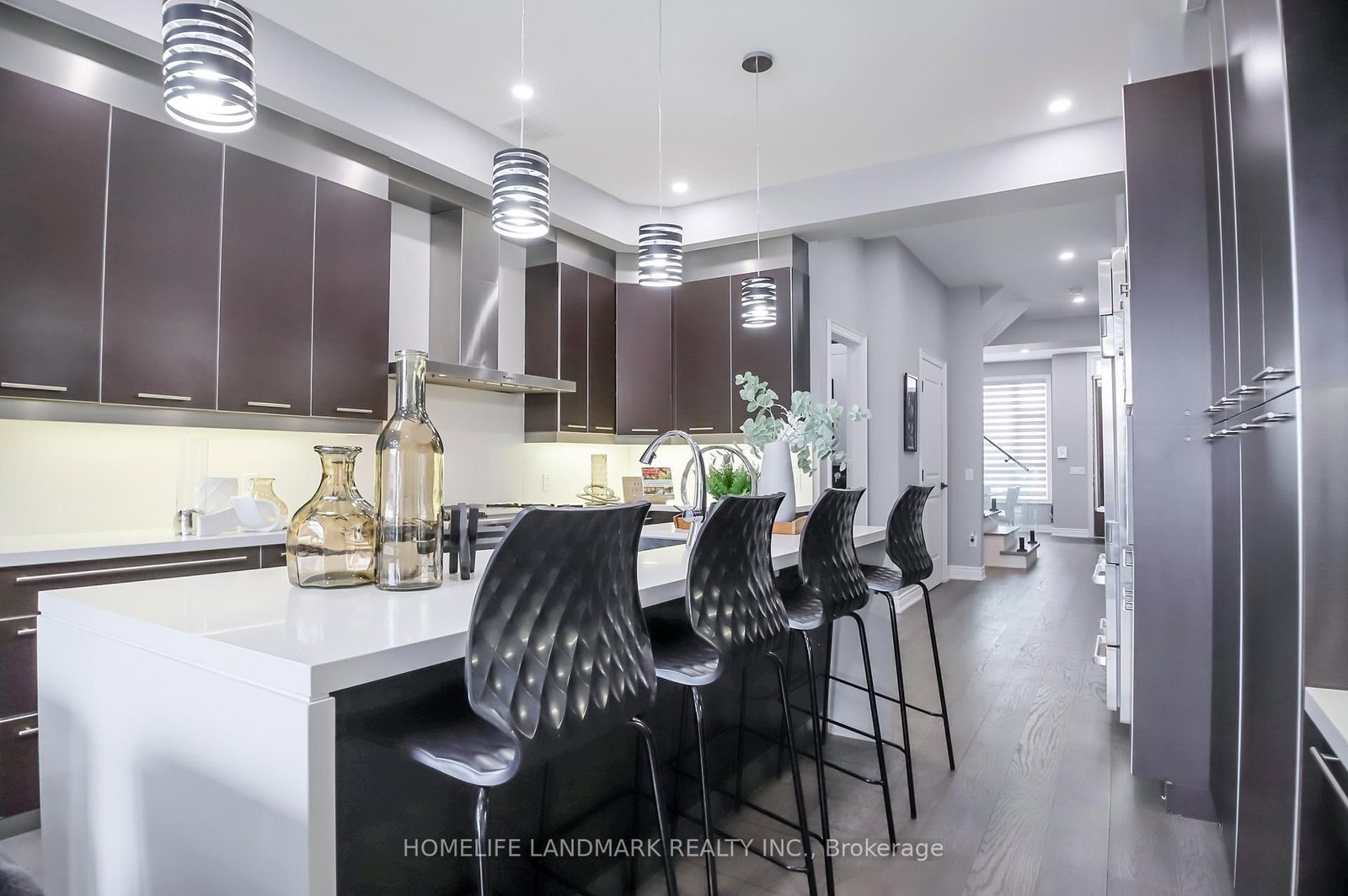 The kitchen at 1733 Kingston Road — Wolf gas range, dark cabinetry, pendant lights and island bar stools