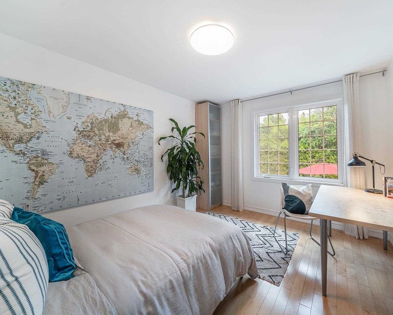 Bedroom with world map wall, desk, and garden view