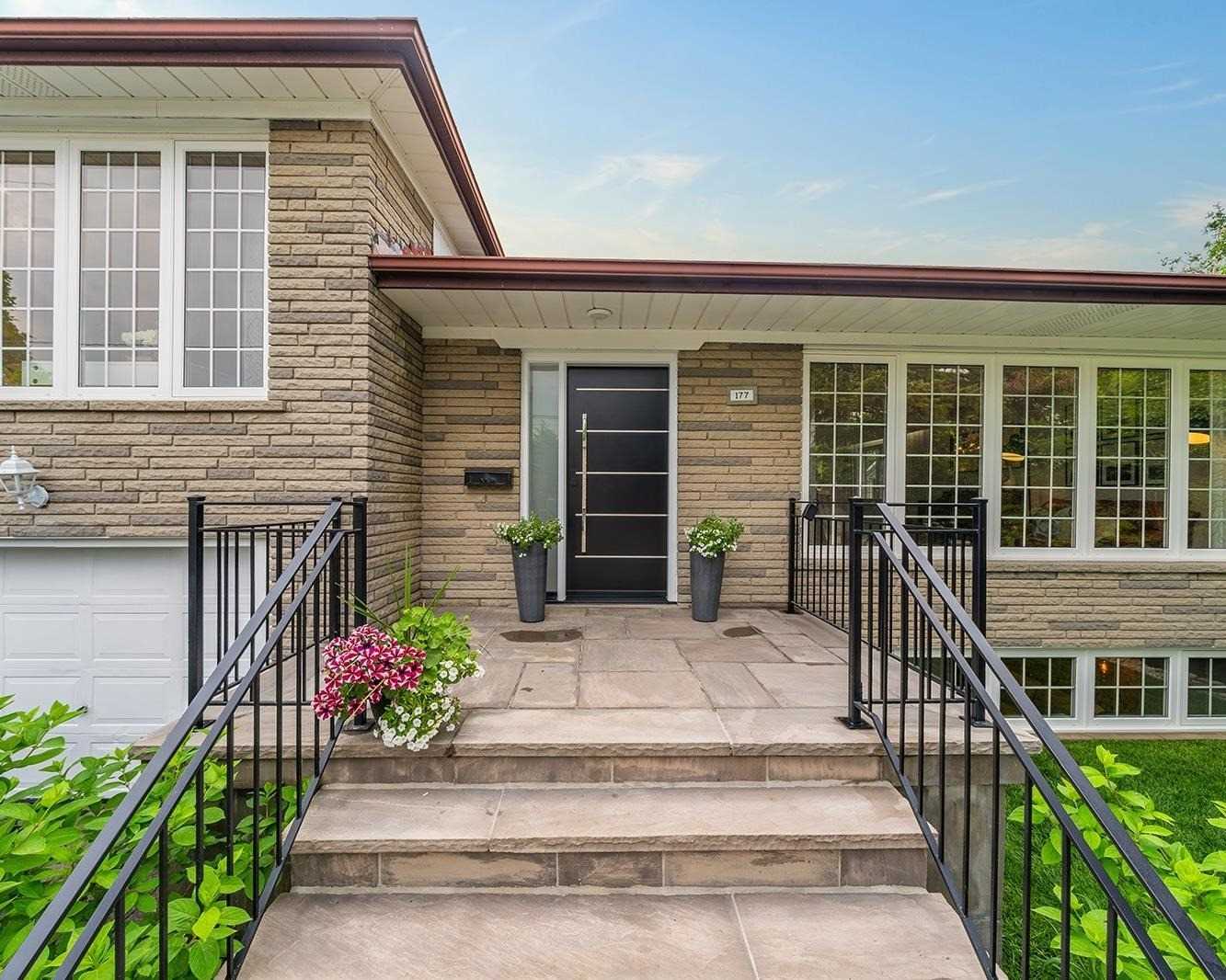 Front porch with black door, stone steps, planters, and address plaque 177