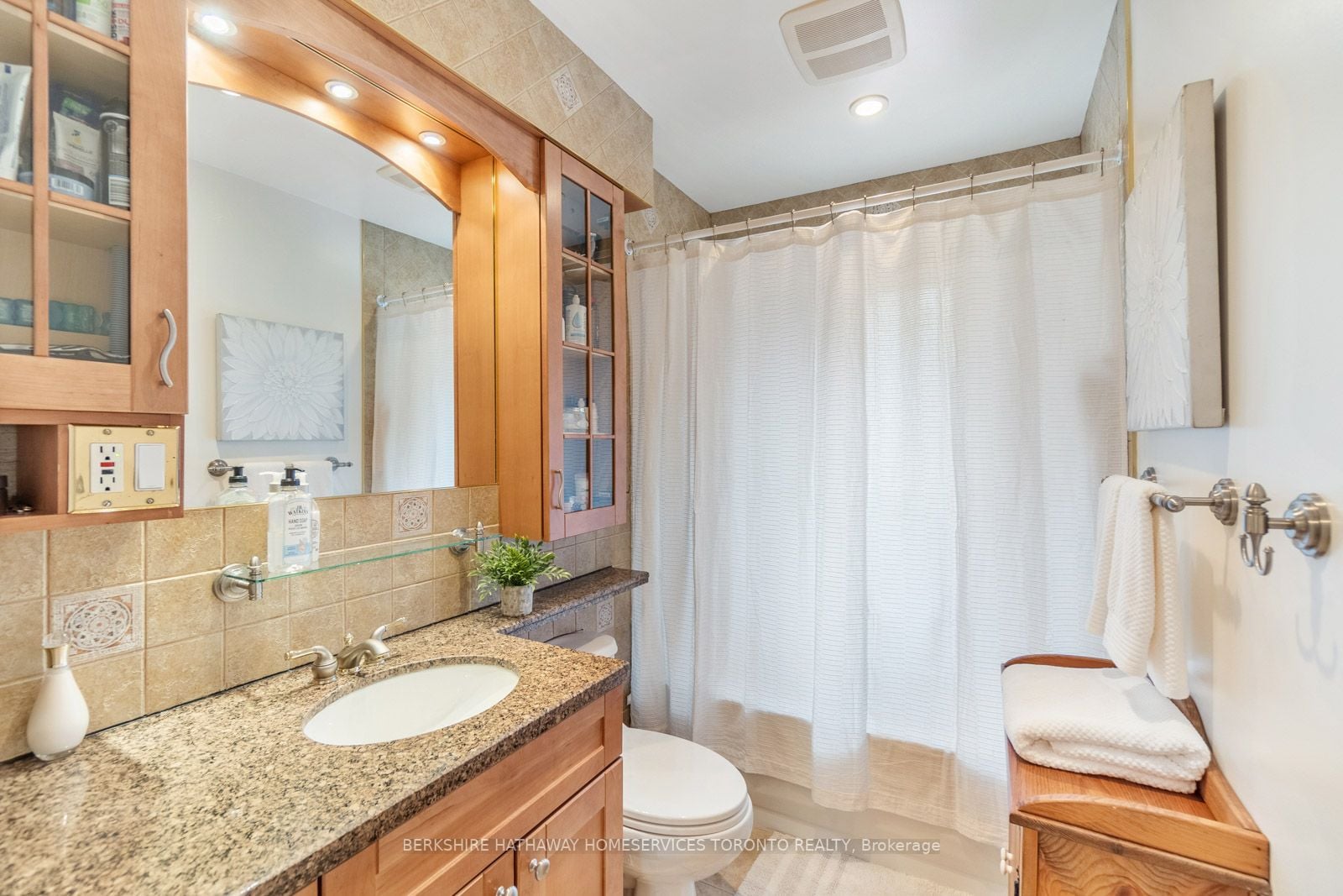 Main bathroom with wood vanity, granite countertop, and tiled tub surround