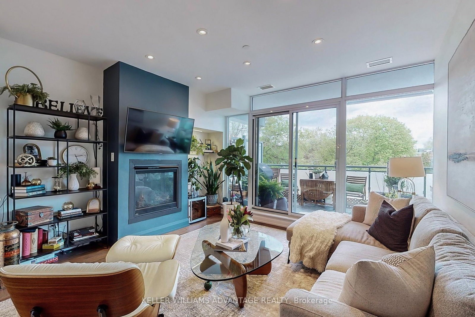The living room at 308 - 200 Woodbine Avenue — fireplace, built-in shelving and glass doors opening to the terrace