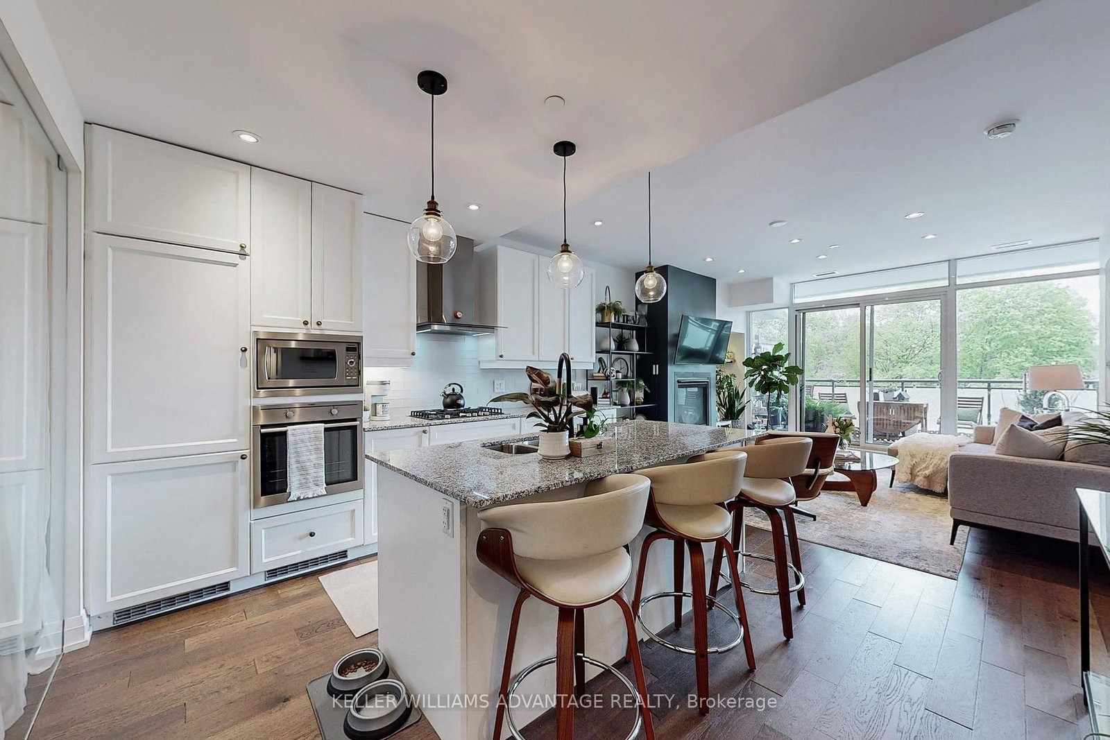 The kitchen at 308 - 200 Woodbine Avenue — white cabinetry, island with seating and stainless steel appliances