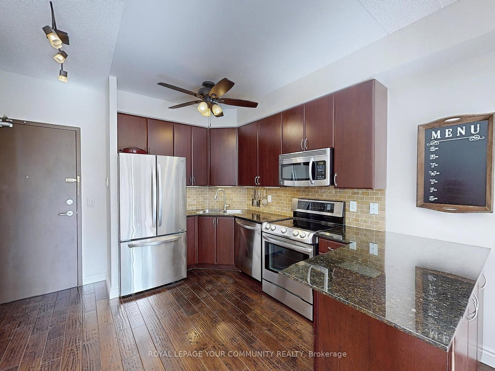 Kitchen of the loft with dark wood cabinetry, stainless steel appliances and granite counters