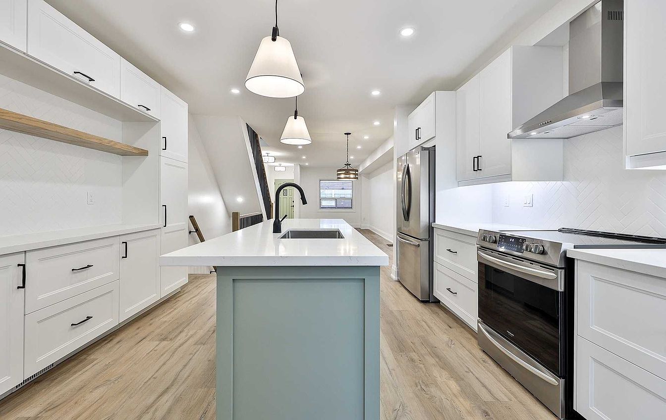 Renovated kitchen with white shaker cabinets, sage green island, quartz counters and stainless steel appliances
