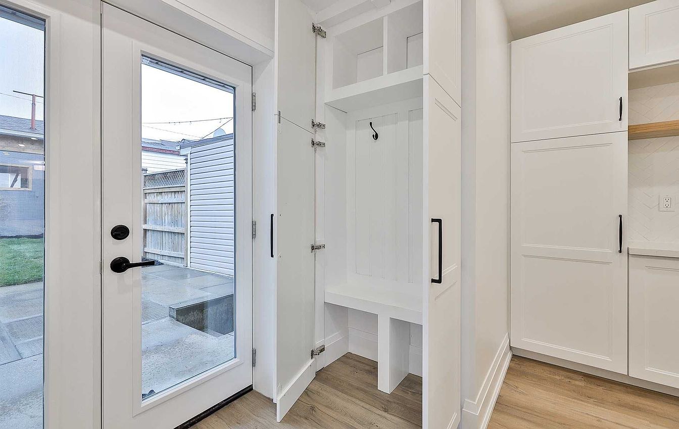 Mudroom with white built-in storage bench and glass door to the backyard