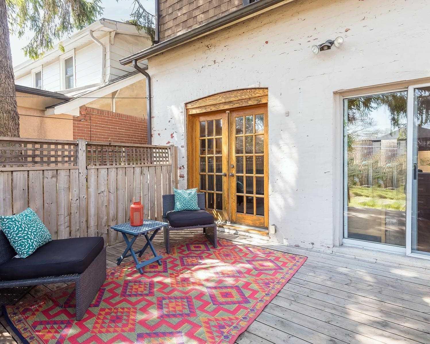 Rear deck of 37 Wheatfield Road with patio furniture, a colourful rug, and French doors