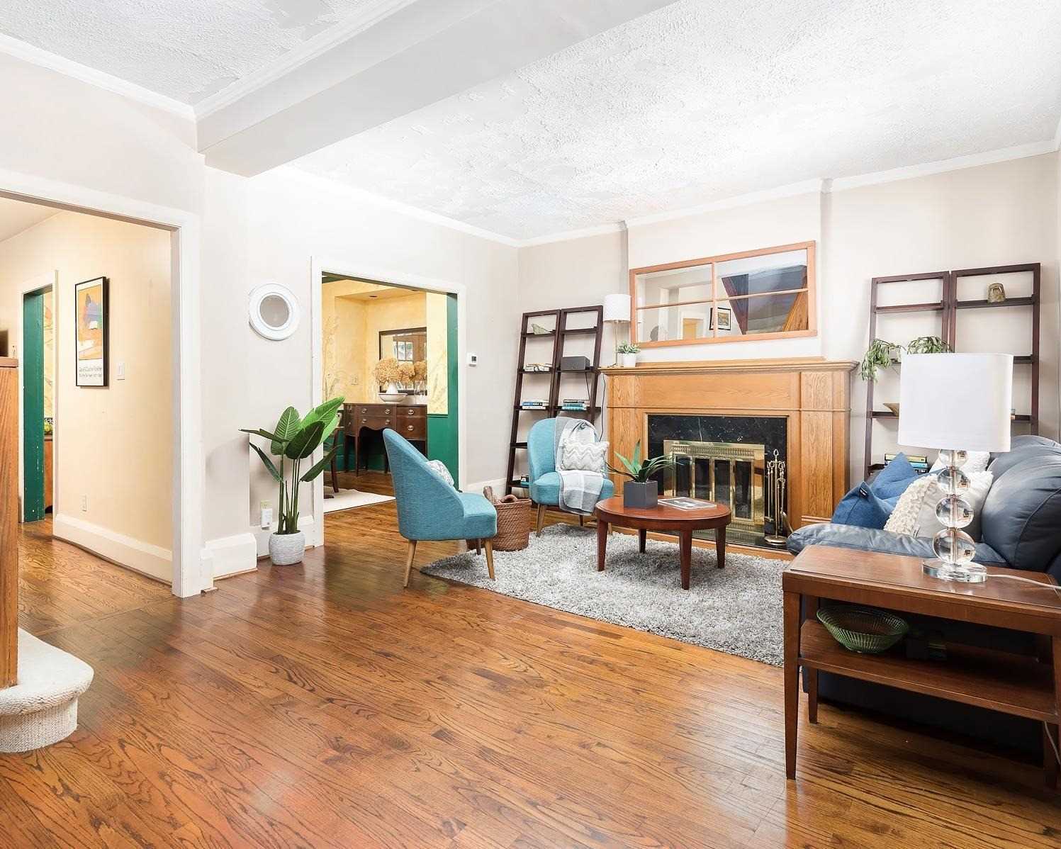 Living room of 37 Wheatfield Road with a wood-burning fireplace, hardwood floors, and blue armchairs