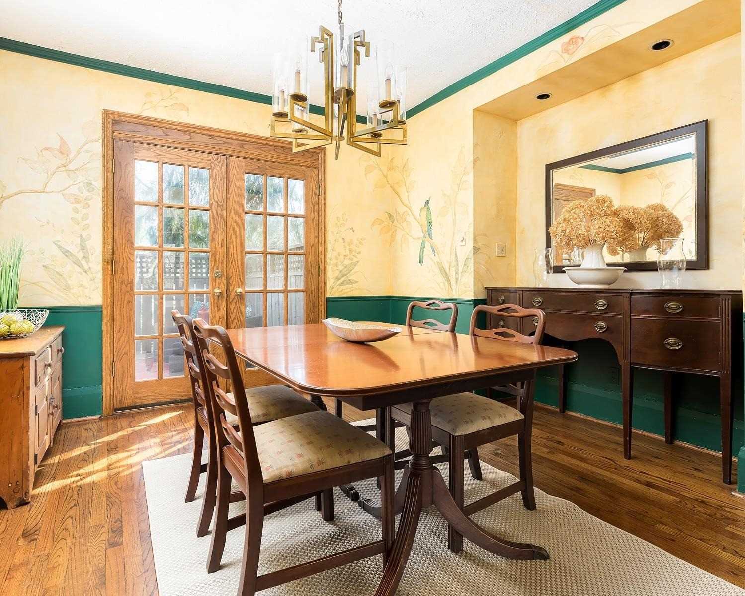 Dining room of 37 Wheatfield Road with yellow walls, green wainscoting, and French doors to the deck
