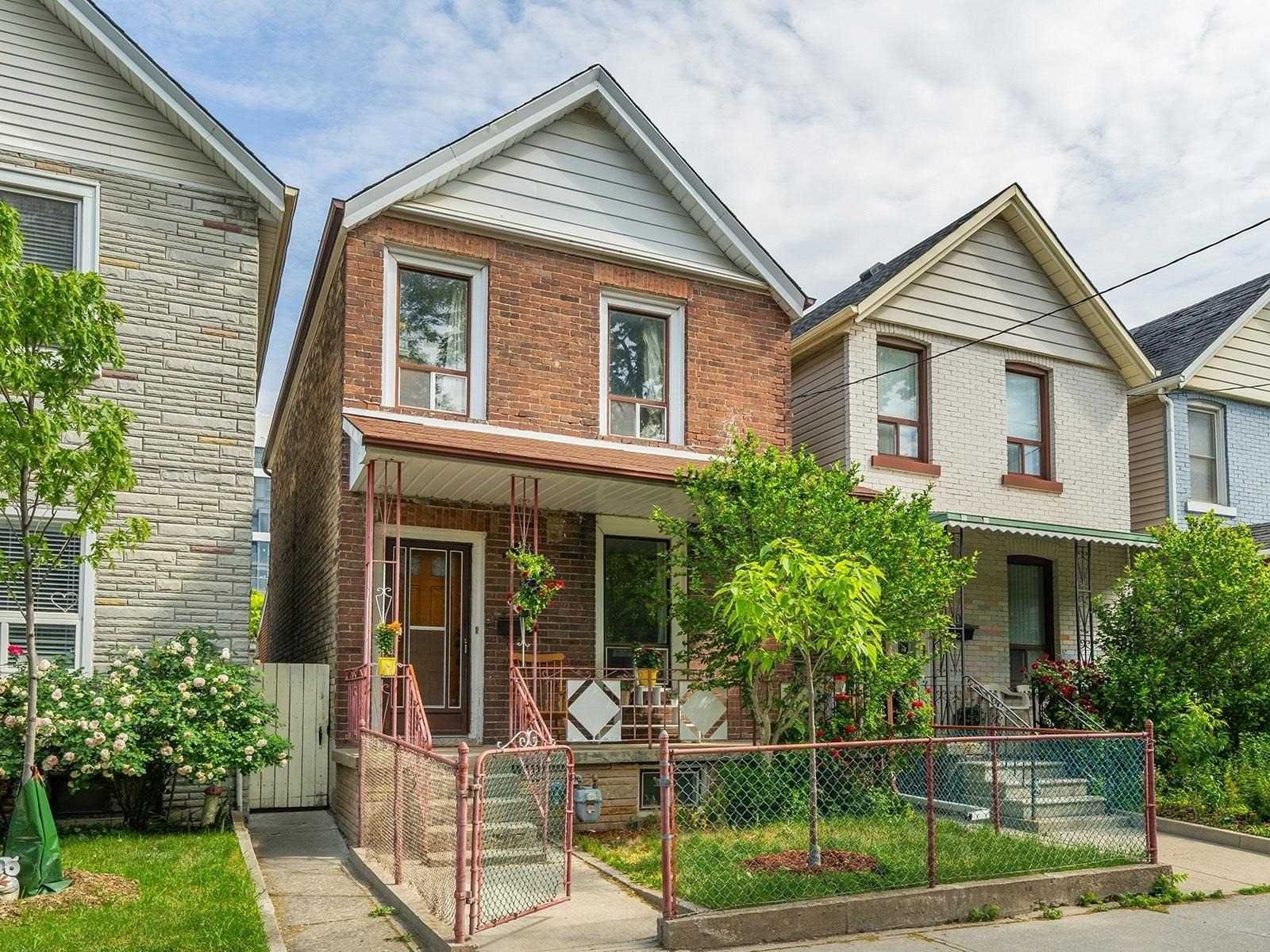 Front exterior of 42 Melville Avenue, a detached brick 2-storey with a covered porch and garden on a Dupont/Christie street
