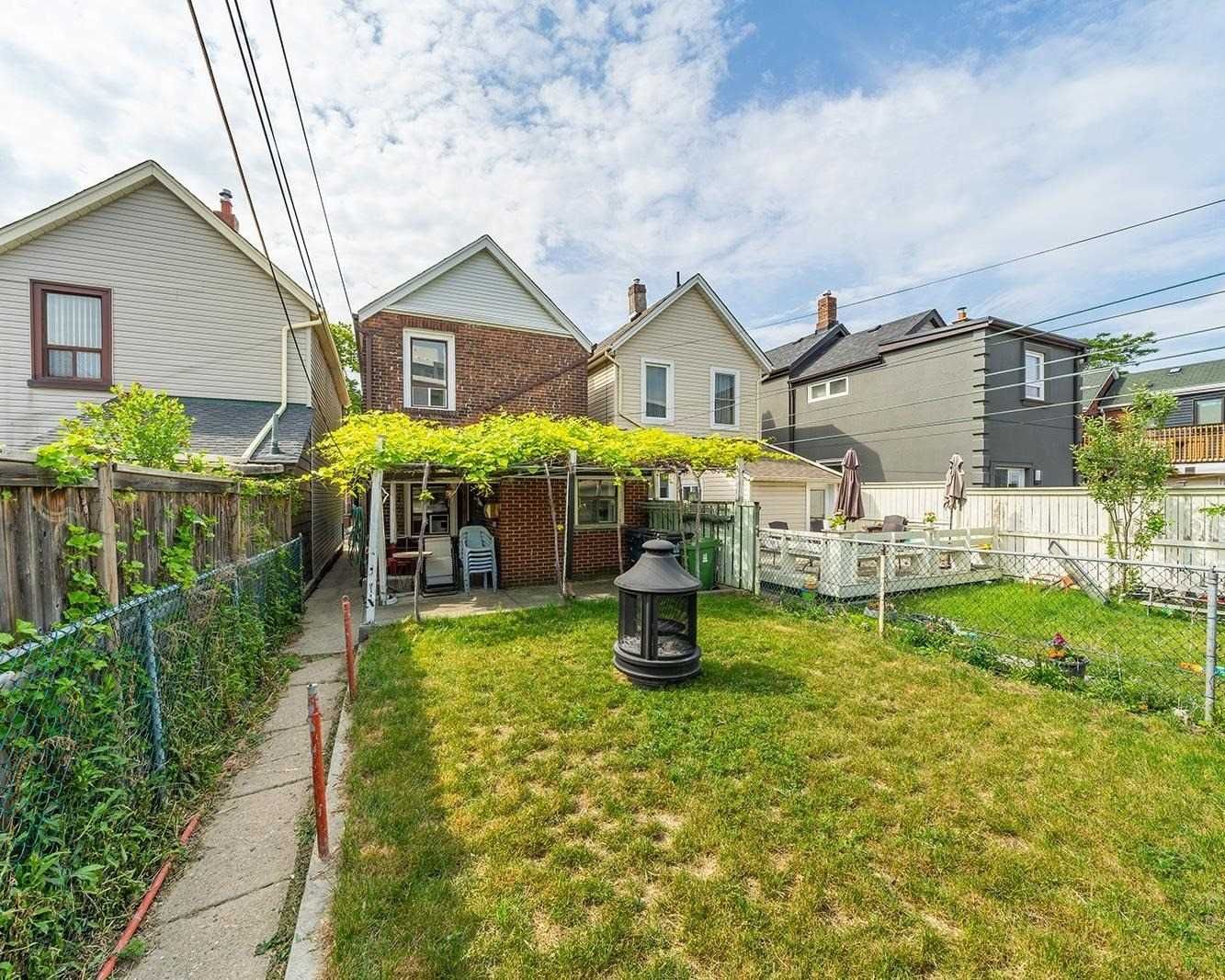 Rear view of 42 Melville Avenue from the backyard, with a grapevine-covered pergola, patio, and chiminea