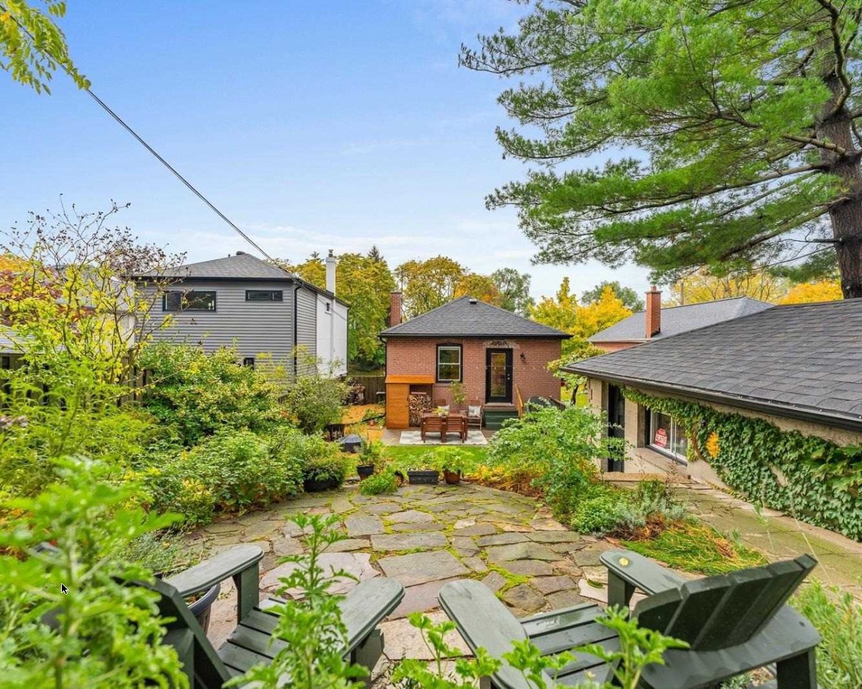 The backyard oasis at 64 Delroy Drive — stone patio, mature gardens and the separate detached garage