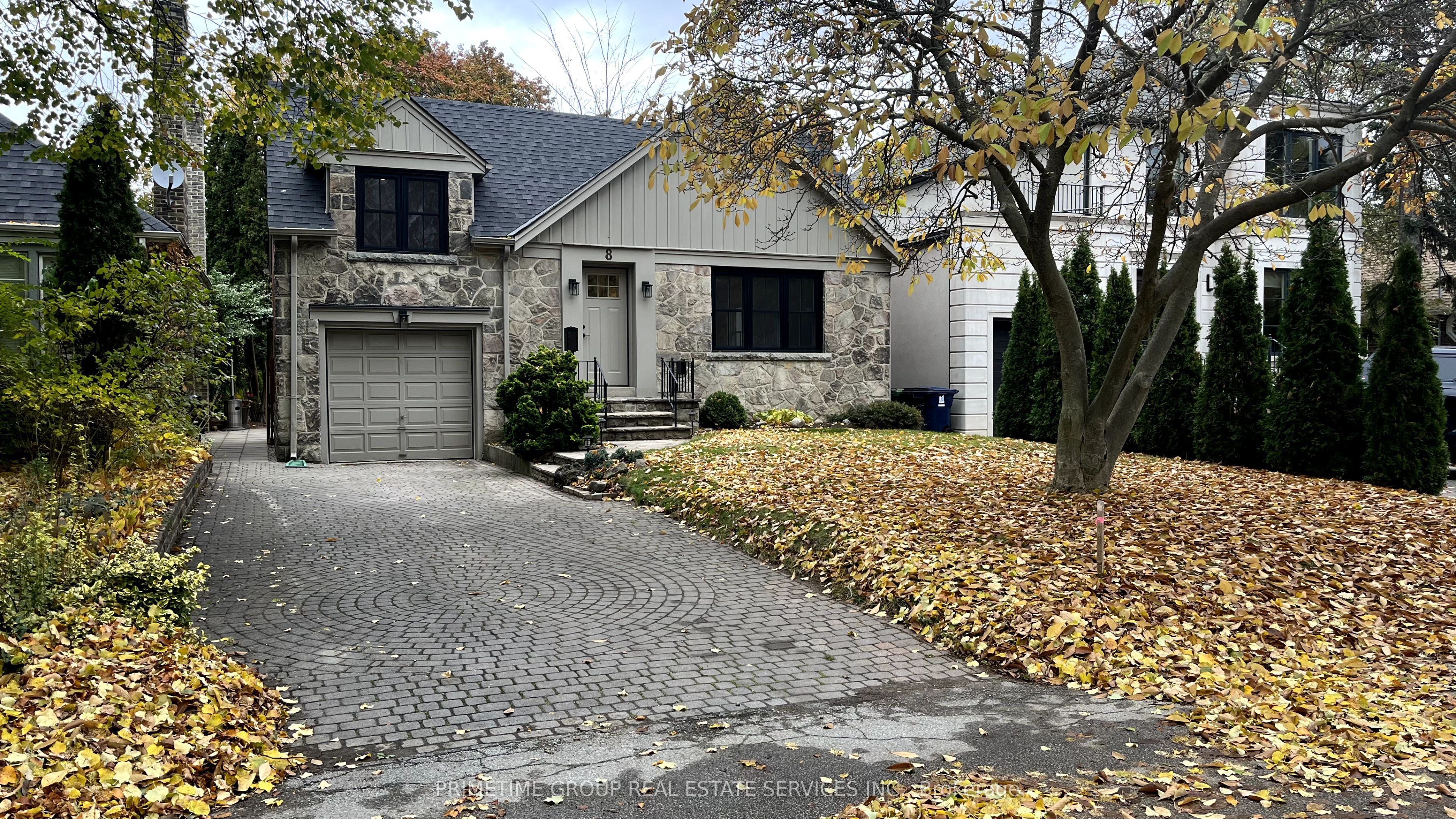The front of 8 Meadowcrest Road, Etobicoke — stone-fronted bungalow with built-in garage and interlock driveway on an autumn day