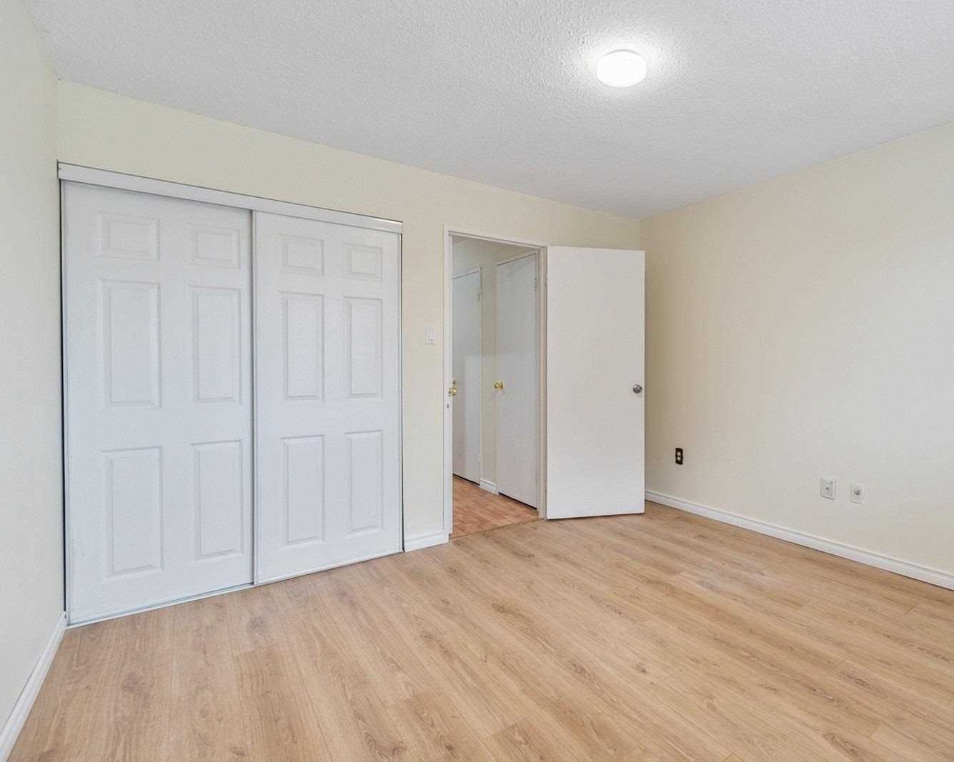 Primary bedroom with double closet doors and laminate flooring