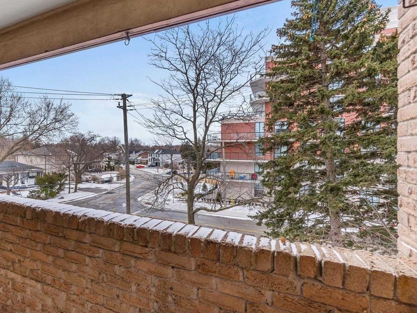 View from the enclosed balcony over the brick parapet toward the street and trees
