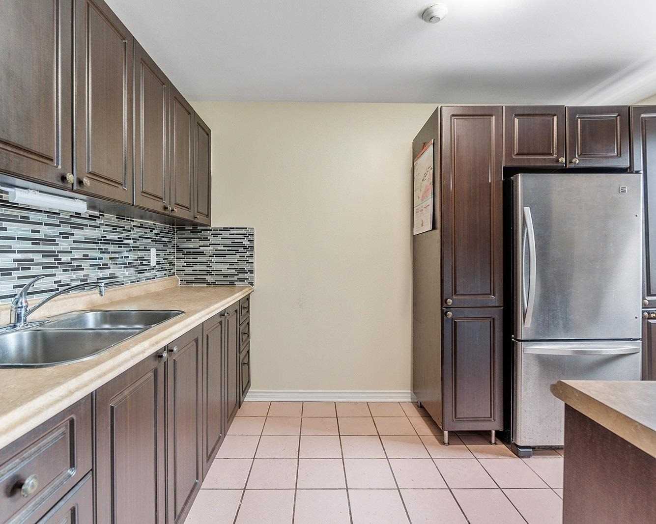 Eat-in kitchen with dark cabinetry, mosaic tile backsplash, and stainless steel fridge
